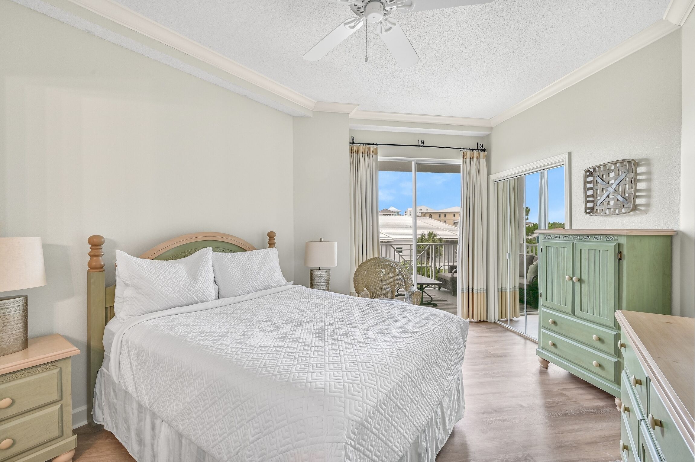 A bedroom with a bed, dresser, and a view of the outside.