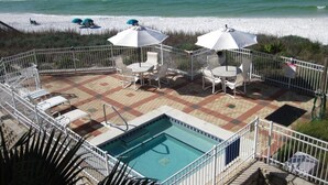 Ein Poolbereich mit Blick auf den Strand, Sitzgelegenheiten im Freien und eine umzäunte Terrasse.