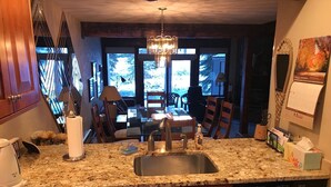 A kitchen with granite countertops, wooden cabinets, a built-in dishwasher, and a dining area with a view of trees. - Gore Creek just off the back deck, Free Bus, Wi-Fi, Hot Tub, Summer Pool (Vail)