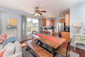 A modern kitchen with wooden cabinets, a dining table with benches, and a ceiling fan.