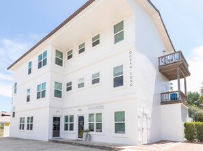 A white building with multiple windows and a balcony on the right side.