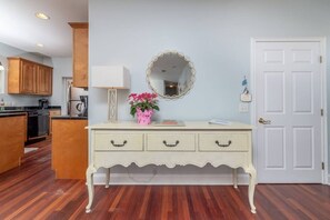 Une pièce avec une commode blanche, un miroir, une porte et des armoires en bois.