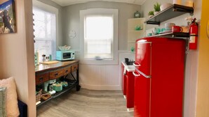 A kitchen with a red refrigerator, a microwave, and a window with blinds. - Marathon Historic Apartments-heart of Downtown - Charming 1 bedroom (Seward)