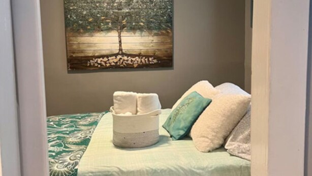 A bedroom with a bed, pillows, a bedside table, and a wall-mounted painting. - Marathon Historic Apartments-heart of Downtown - Charming 1 bedroom (Seward)
