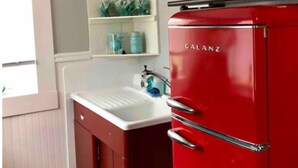 A compact kitchen with a red refrigerator, white cabinetry, a sink, and a window. - Marathon Historic Apartments-heart of Downtown - Charming 1 bedroom (Seward)