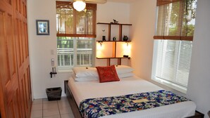 A bedroom with a bed, a wooden door, a window with blinds, and a wall-mounted shelf with decorative items. - Waterfront Luxury Living Inside & Out, Gulf View, On the Water!! (Marathon)