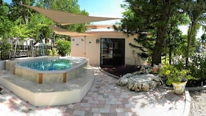 A swimming pool with a sunshade, a brick patio, and a garden with rocks and plants. - Waterfront Luxury Living Inside & Out, Gulf View, On the Water!! (Marathon)