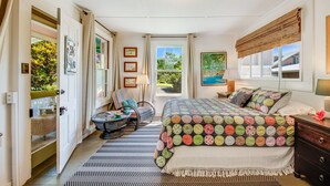 Una camera da letto con un letto, una sedia, una scrivania e una finestra vista sul verde.