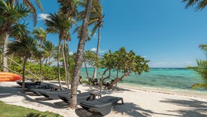 A beach with lounge chairs, palm trees, and a clear view of the ocean. - Akumal Breakers - South Akumal Beach, Mexico (Municipalidad Tulum)