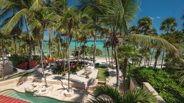A resort with a pool, palm trees, and a beach view.