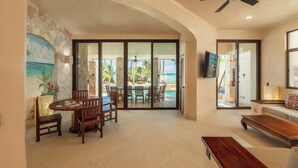 A spacious living area with a dining set, a sofa, and a TV mounted on the wall.