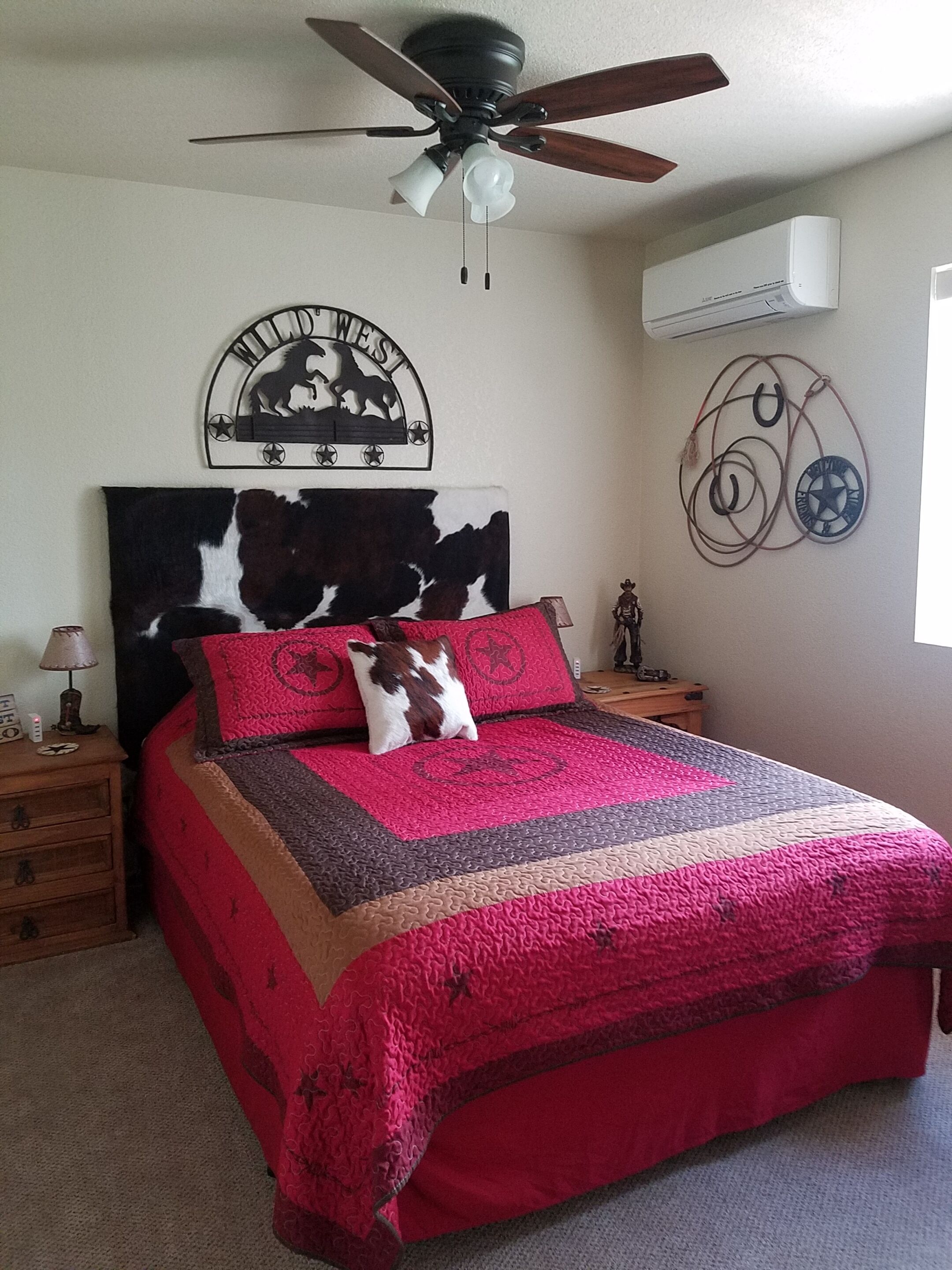 Une chambre à coucher comprenant un lit, un ventilateur de plafond, une horloge murale et un climatiseur fixé au mur.