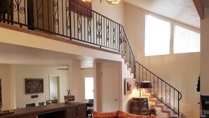 A spacious living area with a high ceiling, a staircase, and a kitchen in the background. -  "Palms to Pines Cabin" - Your home away from home... ☆ 5/5 ☆ Star Rated (Pine)