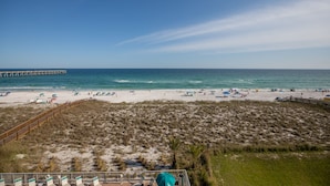 A beach with a wooden boardwalk, sandy dunes, and a pier in the distance. - Navarre's best views from this Regency end unit (Navarre Beach)