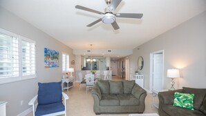 A spacious living room with a ceiling fan, a sofa, a chair, and a dining area in the background. - Navarre's best views from this Regency end unit (Navarre Beach)