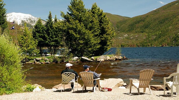 Un entorno junto al lago con dos sillas mirando al agua, una caña de pescar y una bandera.