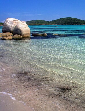 A beach with clear turquoise water, large rocks, and a distant green hill. - Superb villa sea view in an idyllic setting (Zonza)