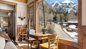 A cozy wooden interior with a dining area, large windows offering a mountain view. - Telluride Riverfront House with Mountain Views (Telluride)