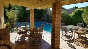A covered patio with a pool, outdoor furniture, and surrounding greenery. - Make Your Friends Jealous (Indio)