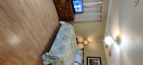 A bedroom with a bed, wooden wardrobe, and a television on a stand. - Make Your Friends Jealous (Indio)