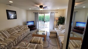 A living room with a sofa set, a coffee table, and two TV screens. - Make Your Friends Jealous (Indio)