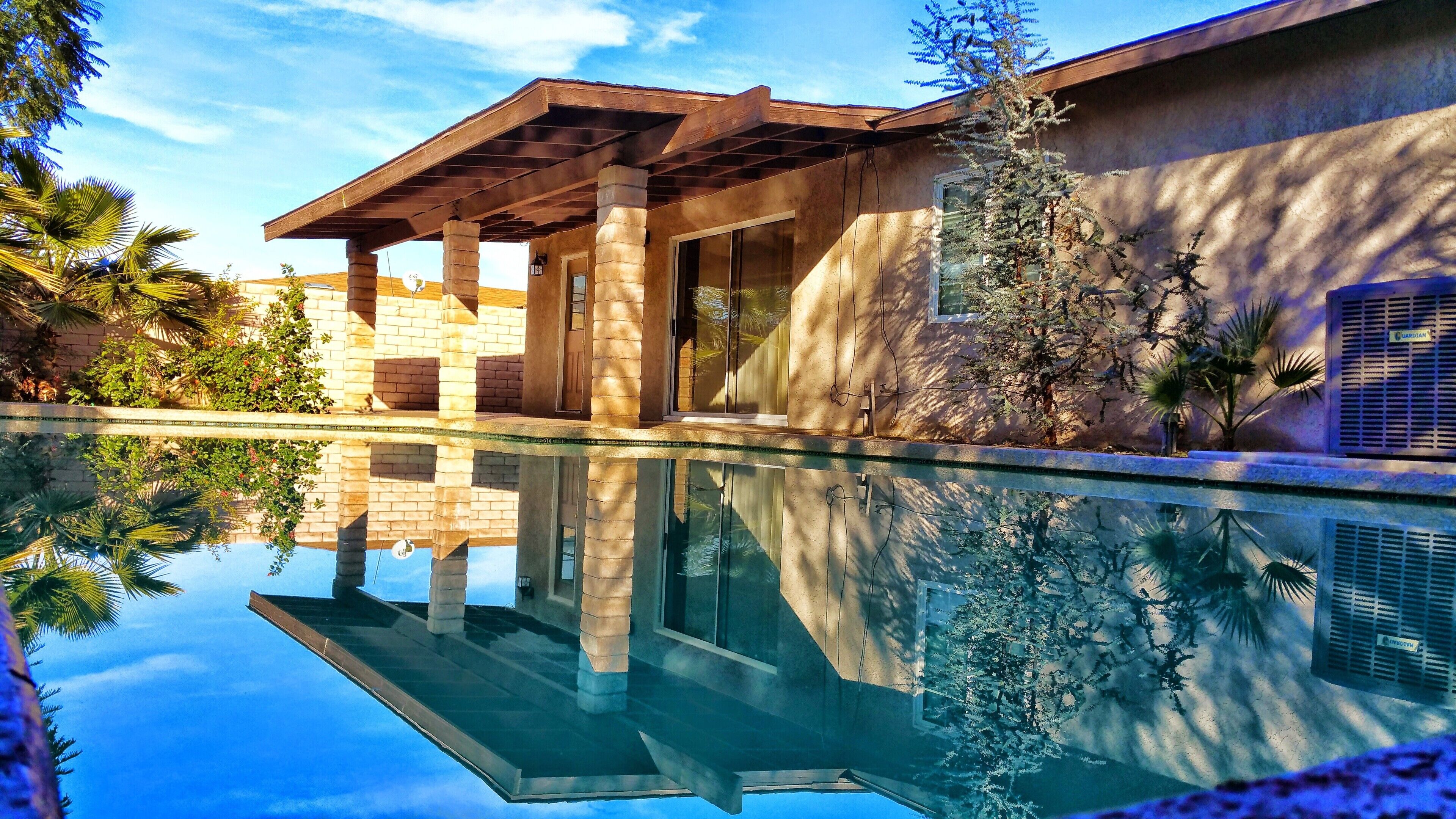 A modern house with a pool, stone pillars, and a pergola.