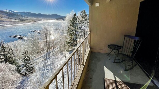 En balkon med udsigt over en flod og bjerge, en stol og et bord.