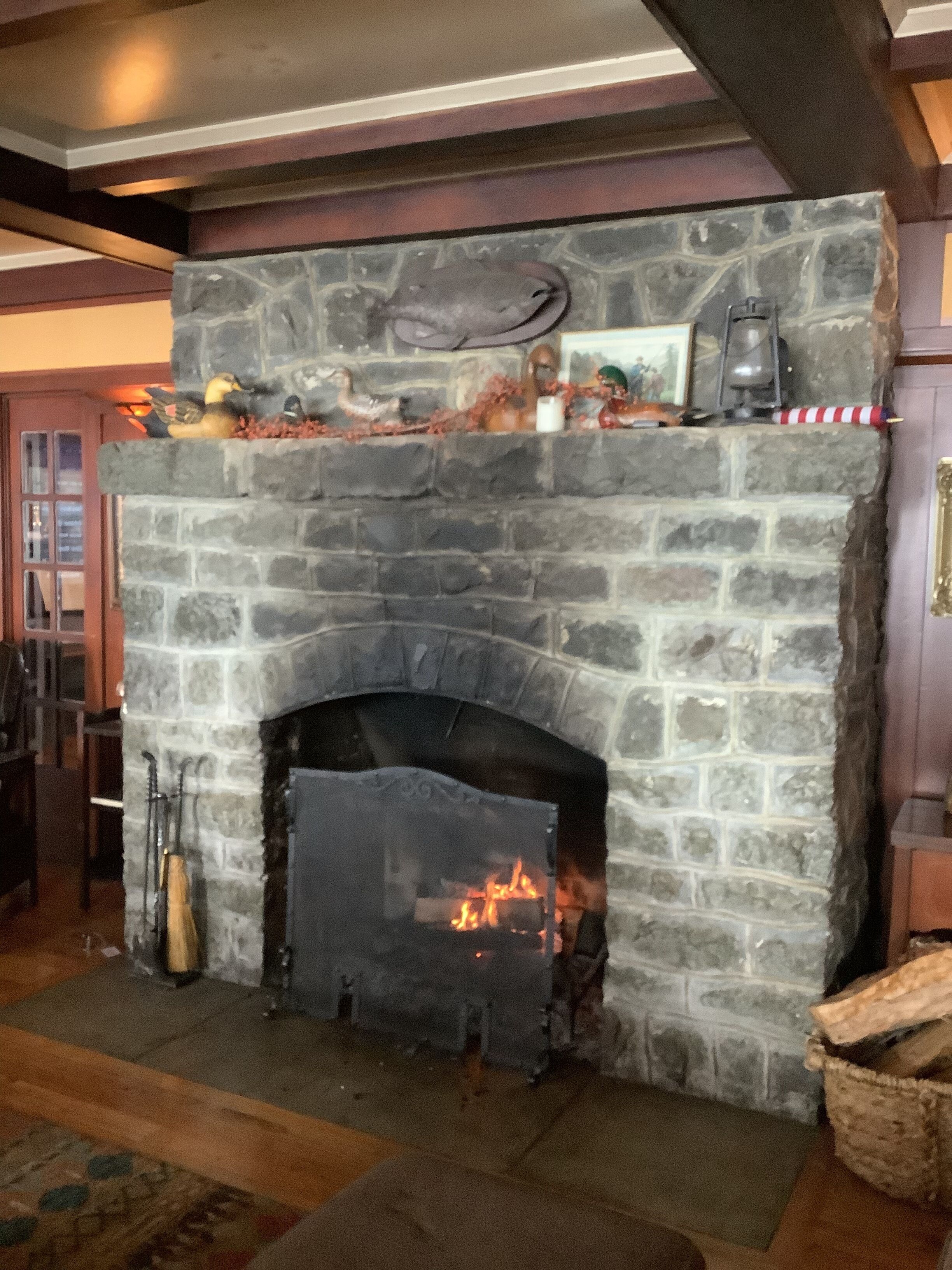 A stone fireplace with a fire, surrounded by a rustic interior.