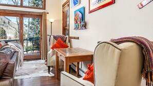 A cozy living room with a large window, a wooden table, and a sofa.