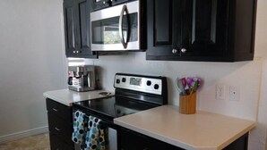 A kitchen with black cabinets, a microwave, a stove, and a coffee maker. - Best location in Kanab! (Kanab)