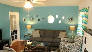 A living room with a sofa, armchairs, a coffee table, and a television. There are decorative mirrors on the wall and a ceiling fan. - Best location in Kanab! (Kanab)