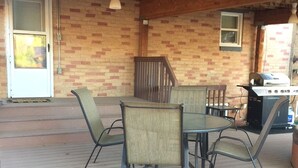 A covered patio with a table and chairs, a grill, and a wooden staircase. - Best location in Kanab! (Kanab)