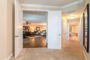 A spacious living room with a wooden floor, a ceiling fan, and a seating area with chairs and a sofa.