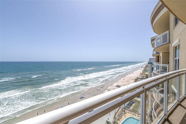 A beachfront hotel with a balcony overlooking the ocean.