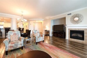 A living room with a fireplace, a television, and a dining area with chairs and a table.