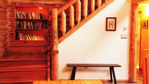 A wooden staircase leading to a loft area with a bookshelf and a bench.