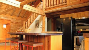A rustic kitchen with a wooden interior, a built-in stove, and a refrigerator.