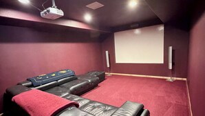 A home theater room with a large screen, reclining seats, and a ceiling projector. - The McCaskell Cabin- Nestled out in the countryside.  (Hill City)