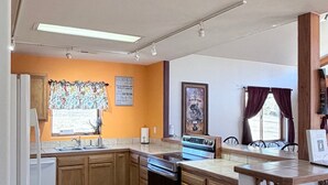 A kitchen with wooden cabinets, a built-in oven, and a window with curtains. - The McCaskell Cabin- Nestled out in the countryside.  (Hill City)