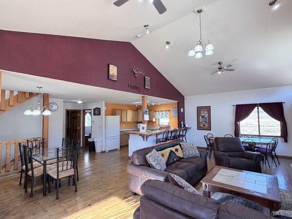 A spacious living area with a dining table, sofas, and a kitchen in the background. - The McCaskell Cabin- Nestled out in the countryside. (Hill City)