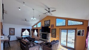A spacious living room with a fireplace, leather sofas, and a dining area. - The McCaskell Cabin- Nestled out in the countryside.  (Hill City)