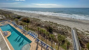 Un resort frente a la playa con piscina, acceso directo a la arena y un paseo marítimo.