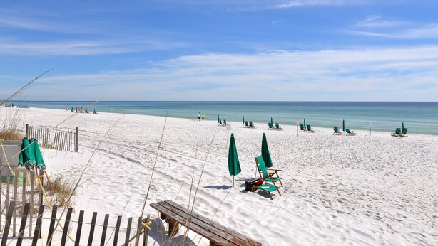 A beach with white sand, green umbrellas, and wooden chairs. - Gulf View, Steps from the Beach, Family Friendly (Destin)