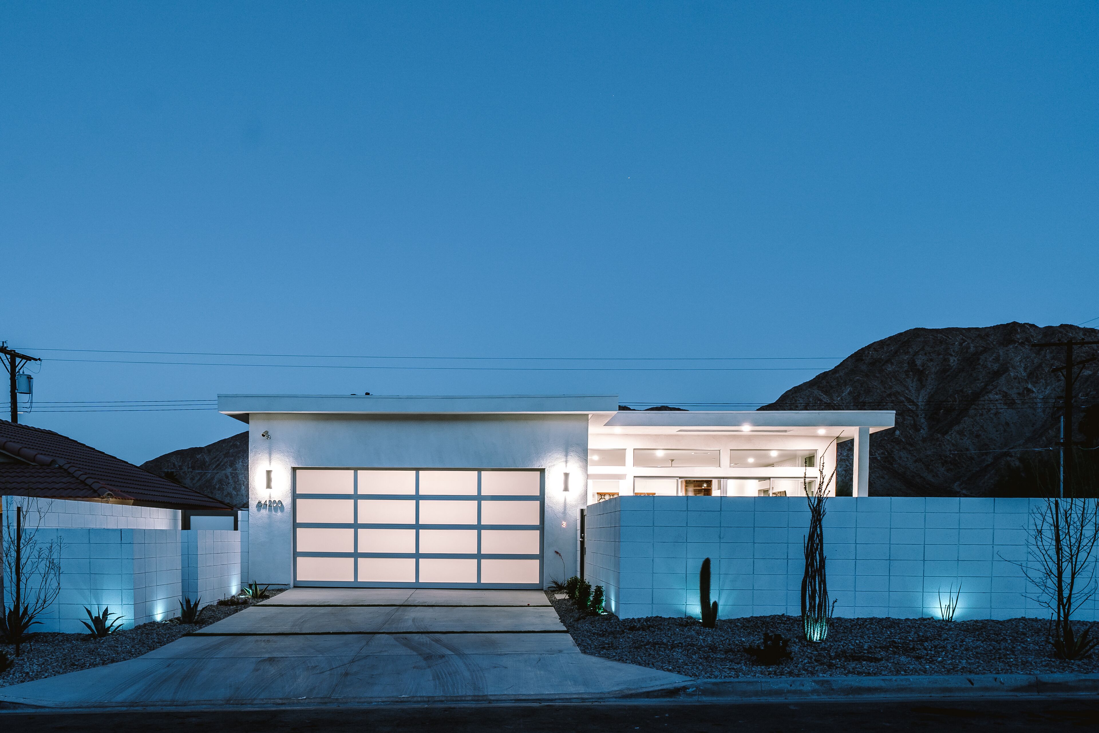 A modern house with a garage, a driveway, and a desert landscape in the background.
