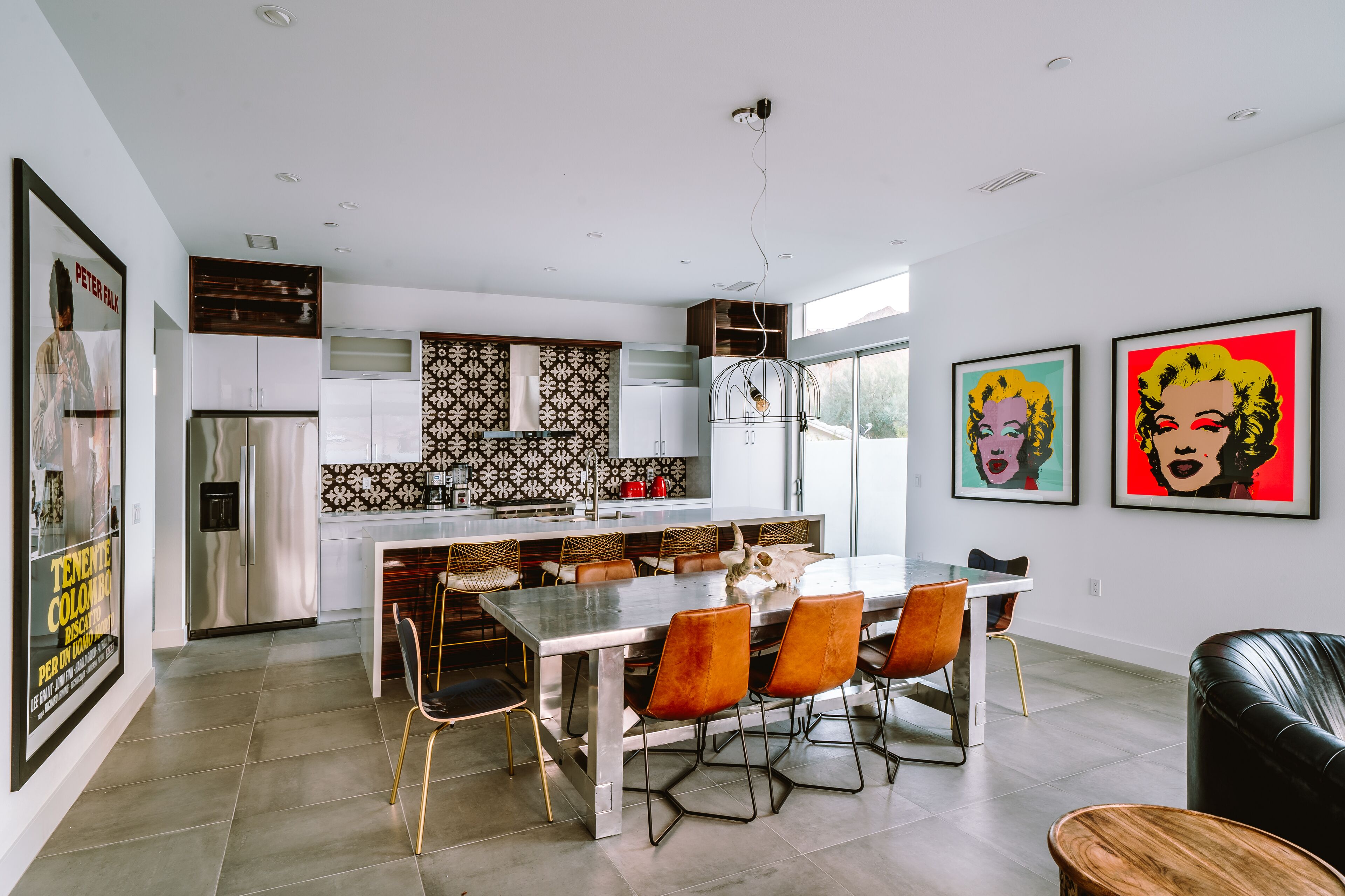 Een moderne keuken met een centraal eiland, roestvrijstalen apparatuur en een decoratieve spatwand.