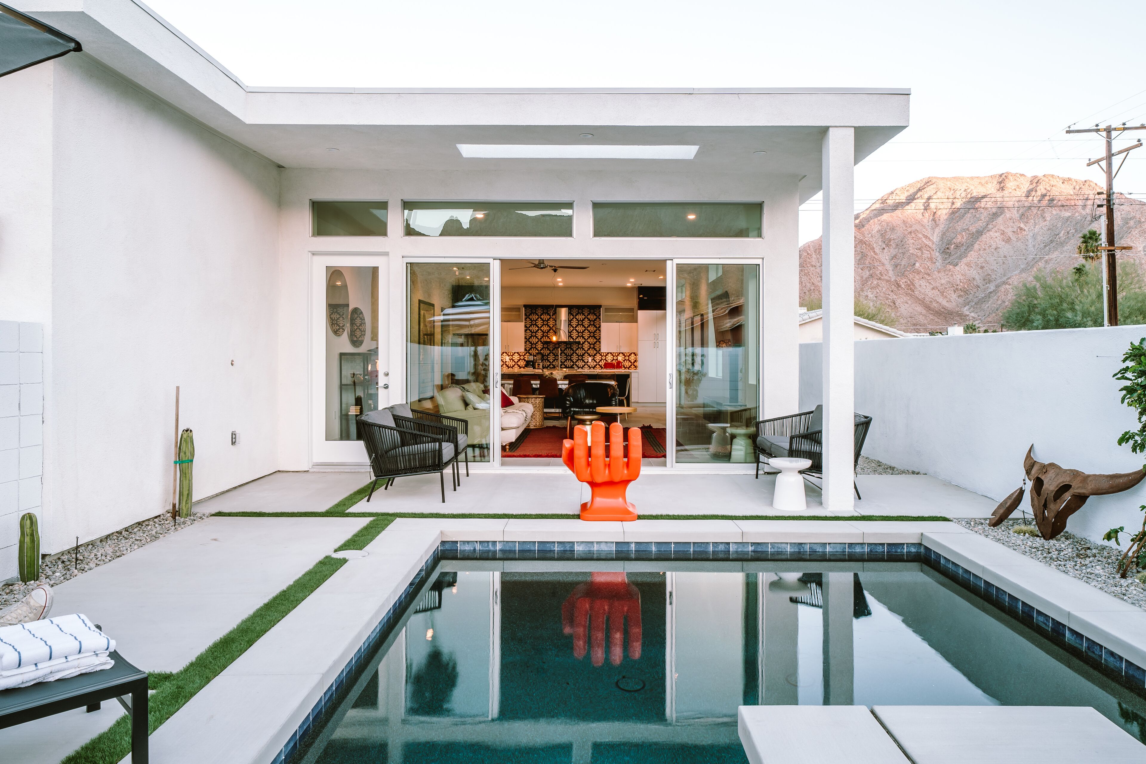A modern house with a pool, outdoor seating, and a mountain view.