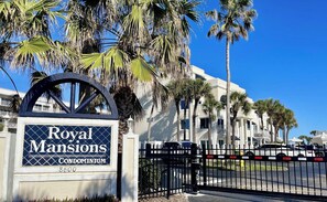 A gated entrance to Royal Mansions Condominium with a clear blue sky in the background.