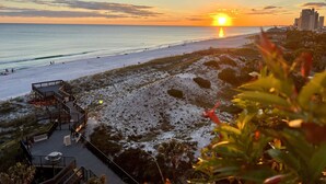 Une plage avec une promenade en bois, un poste de surveillance pour les sauveteurs et une vue sur l’océan au coucher du soleil.
