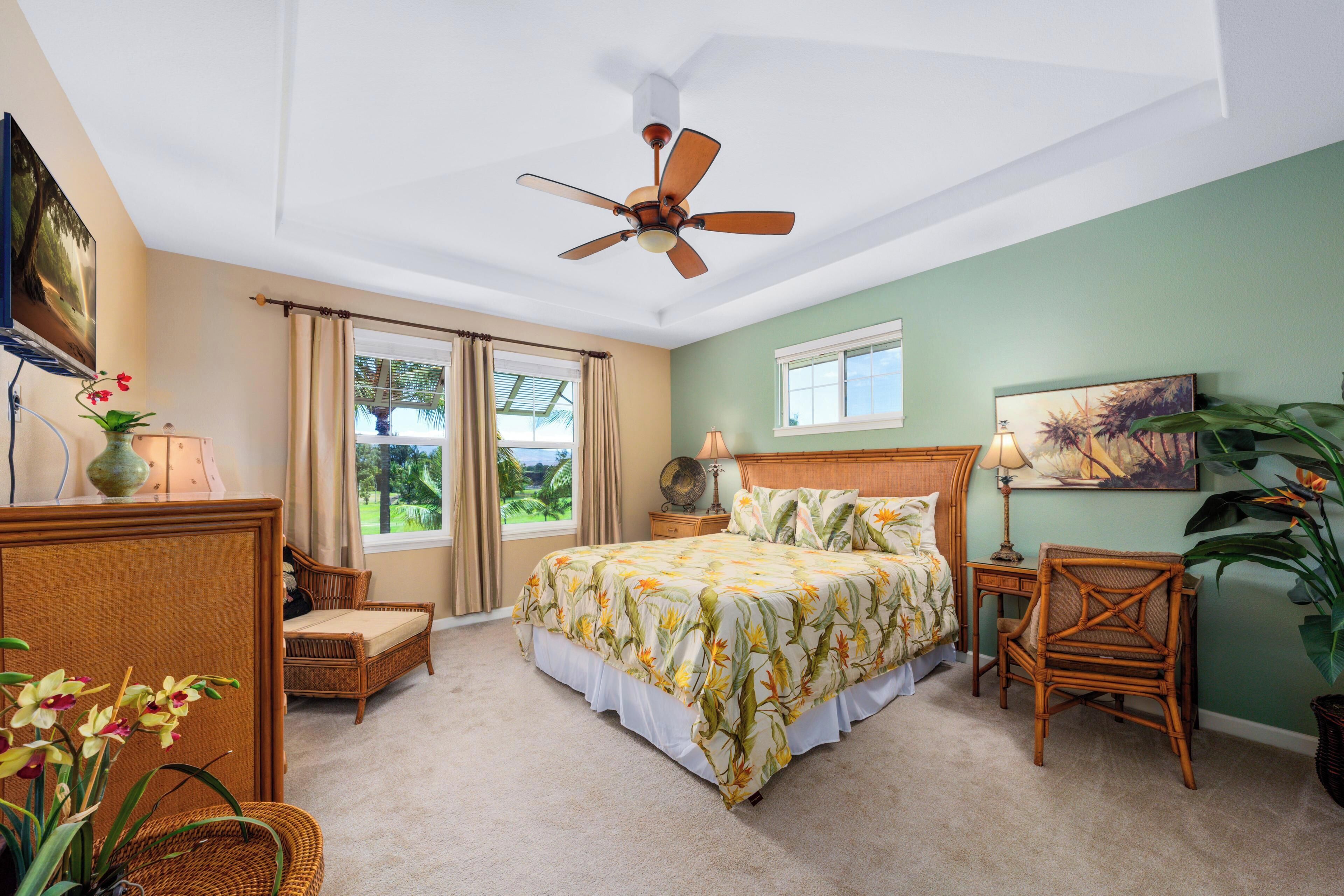 A bedroom with a bed, a ceiling fan, a window, a nightstand, a chair, and a potted plant.