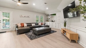 Una sala de estar moderna con un sofá modular, un televisor de pantalla plana montado en la pared y un ventilador de techo.